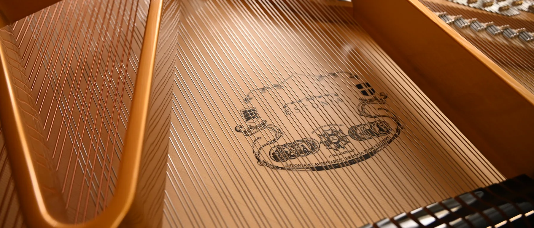 Tabla armónica de un piano Estonia, con el sello de la fábrica grabado bajo las cuerdas