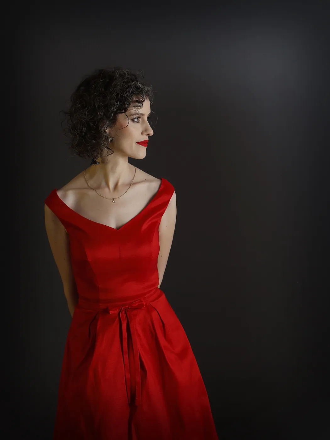 Alicia Sevilla con vestido rojo sobre fondo oscuro